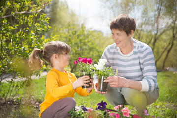 Spring awakening. Slow life. Enjoying the little things. Dreaming of spring. grandmother and child granddaughter plant flowers near the house. Child girl help grandmother work in the garden.