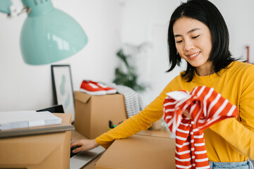 Female young small business asian owner using laptop computer selling clothes online from home....