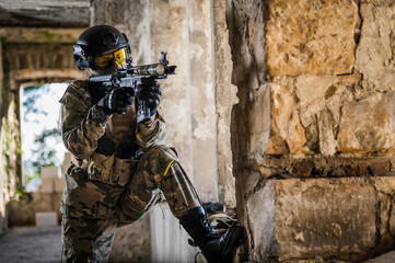 A woman in an army uniform aims to shoot a firearm in an abandoned building. 