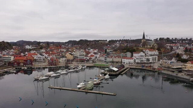 Grimstad marina and city center - Beautiful morning aerial moving slowly backwards over clear sea surface to reveal whole city close to arendal road - Norway