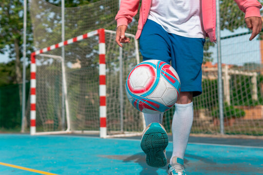 Image of a man kicking the ball with his foot. Close-up image of a young boy hitting the ball with his feet on a blue soccer field with the goal in the background.