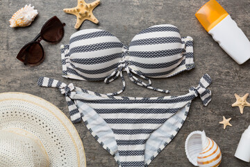 Woman swimwear and beach accessories flat lay top view on colored background Summer travel concept. bikini swimsuit, straw hat and seasheels. Copy space Top view