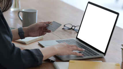 Woman holding credit card and using laptop computer for online shopping, e-commerce, internet banking.