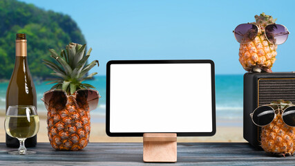 Digital tablet and  summer drinks on wooden table with tropical beach in background. Summer holiday concept.