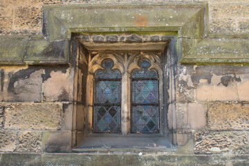 Stone window frame with stained glass diamond shapes held in by lead in a medieval church from the 12th century England