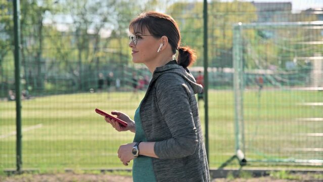 Active Mature Woman In Sportswear With Smartphone, Outdoor, Profile View