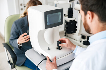 Obraz premium Male ophthalmologist checks a patient's vision at an opticians shop or ophthalmology clinic