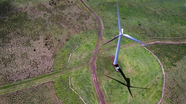 A wind turbine generating clean energy from the Hawi Renewable Development wind farm - orbiting aerial view