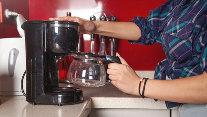Woman making coffee in a coffee maker machine.