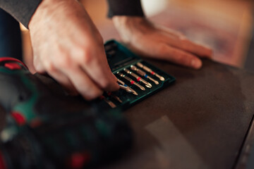 Focus on the drill bits, the man choosing the right for his dril