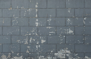 The wall of the building is made of gray brick with old cracked paint. Architecture and construction. Background for designers.