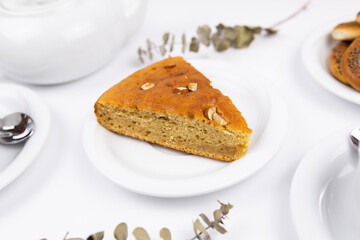 A piece of cake on a saucer with a cup for tea or coffee and a kettle