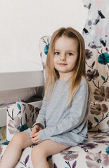 Portrait of 4 years old girl. Small girl sitting in armchair with floral ornament. Selective focus. Film grain