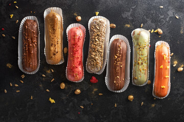 Traditional French dessert. Assorted eclairs on a dark stone background. flat lay, banner