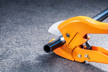 Plumber cuts the plastic pipe using a cutter. Repair water system concept.
