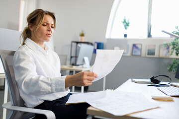 Business woman examines documents while sitting at the office workplace