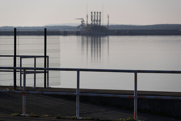 SEAPORT - Fences on breakwater with LNG terminal in the background
