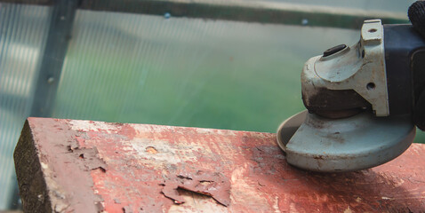 a man is grinding a board. Removing old paint from boards. Carpentry work.
