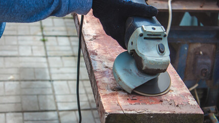 a man is grinding a board. Removing old paint from boards. Carpentry work.