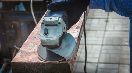 a man is grinding a board. Removing old paint from boards. Carpentry work.
