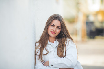 Portrait of a young happy beautiful woman with long hair in light casual comfortable clothes outside.