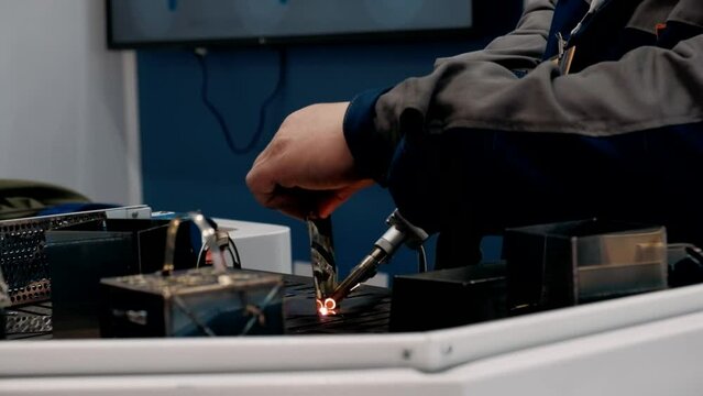 Welder hands using portable handheld laser welding machine with sparks - close up view. Metalworking, industrial