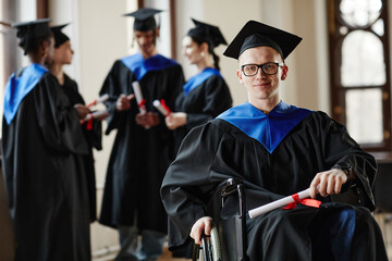 Portrait of young man with disability at graduation ceremony in university, copy space - obrazy, fototapety, plakaty