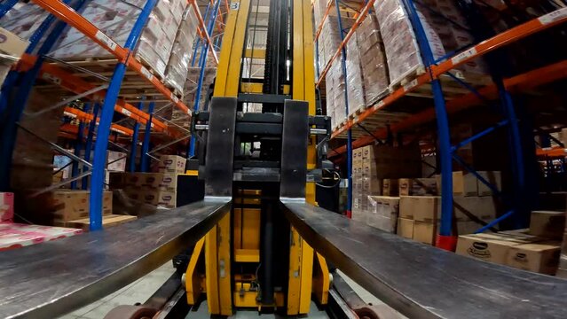 The load lifter rides on the warehouse pov. Forklift fork close-up. Modern forklift in a large warehouse