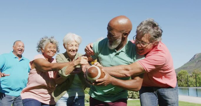 Happy senior diverse people playing rugby in garden at retirement home