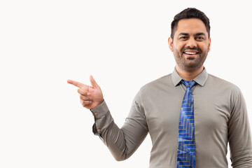 Cheerful young businessman pointing against white background