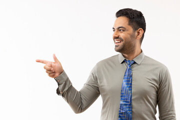 Cheerful young businessman pointing against white background