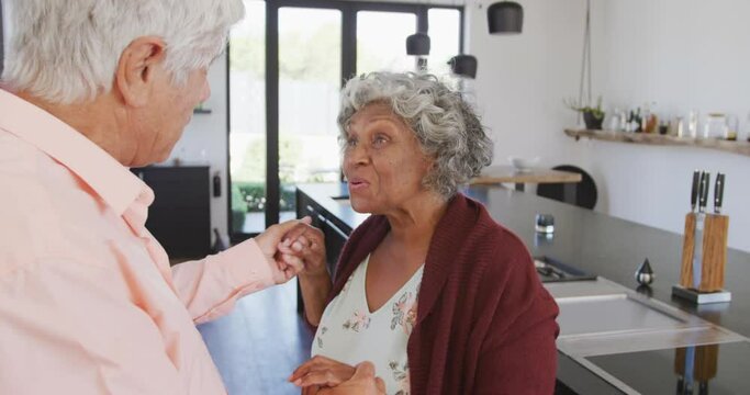 Happy senior diverse couple dancing in kitchen at retirement home