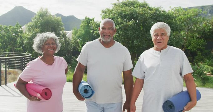 Portrait of happy senior diverse people practicing yoga in garden at retirement home