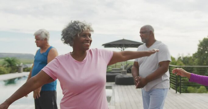 Happy senior diverse people practicing yoga in garden at retirement home