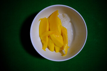 Yellow sticky rice with mango, orange and white cream. Tasty sweet food taste concept. Natural food culture and nutrition. Healthy vegetarian dish concept. Thailand food style, sweet and sweet mango