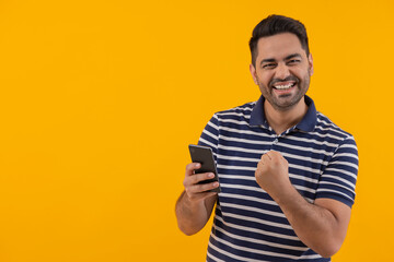 Portrait of happy young man cheering with raising his fist