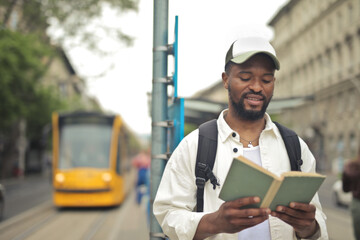 young man reads a book in a tram station