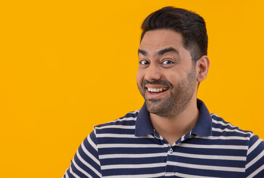 Portrait Of Smiling Young Man With Raised Eyebrows Against Yellow Background