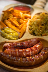 Spicy smoked sausages with cheese served with french fries and pickled onions - traditional pub snack
