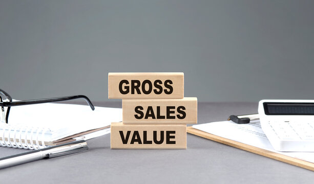GSV - Gross Sales Value text on wooden block with notebook,chart and calculator, grey background