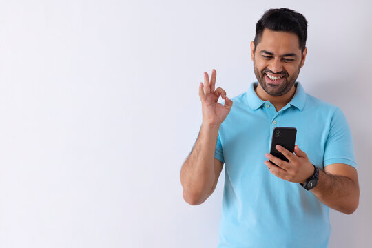 Cheerful young man showing Ok hand gesture while talking to video call on Smartphone