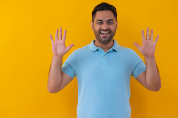 Portrait of a cheerful young man showing number with his fingers against yellow background