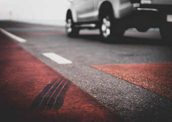 wheel traces on the road with blurred car in background, safety road and insurance concept