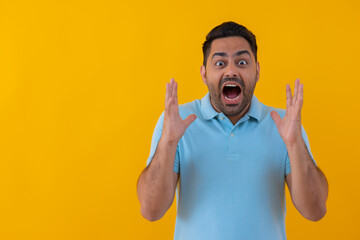 Portrait of an angry young man shouting against yellow background