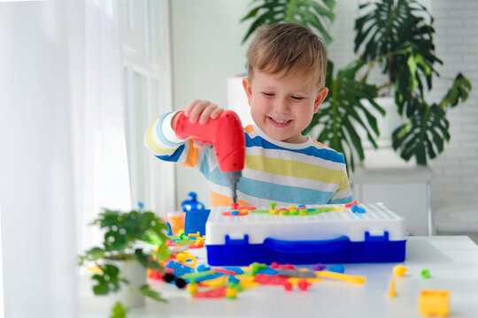 Little Boy Playing Set With A Screwdriver And A Drill,  And Screws And Parts . The Child Plays Builder With A Toy Drill To Develop Imagination And Motor Skills. Educational Logic Toys For Children.