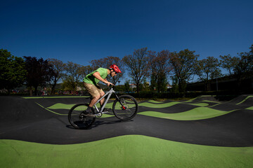 side view of an expert biker training on a paved pump track circuit