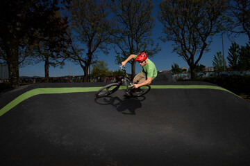 biker on an asphalt pump track circuit going over a banked cant