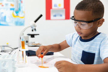 African american elementary boy performing chemical experiment while wearing protective glasses