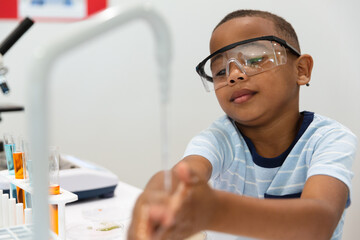 African american elementary boy washing hands during chemistry laboratory class - Powered by Adobe