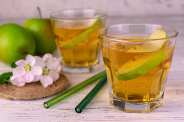 Fresh apple juice in glasses on a white wooden background.
